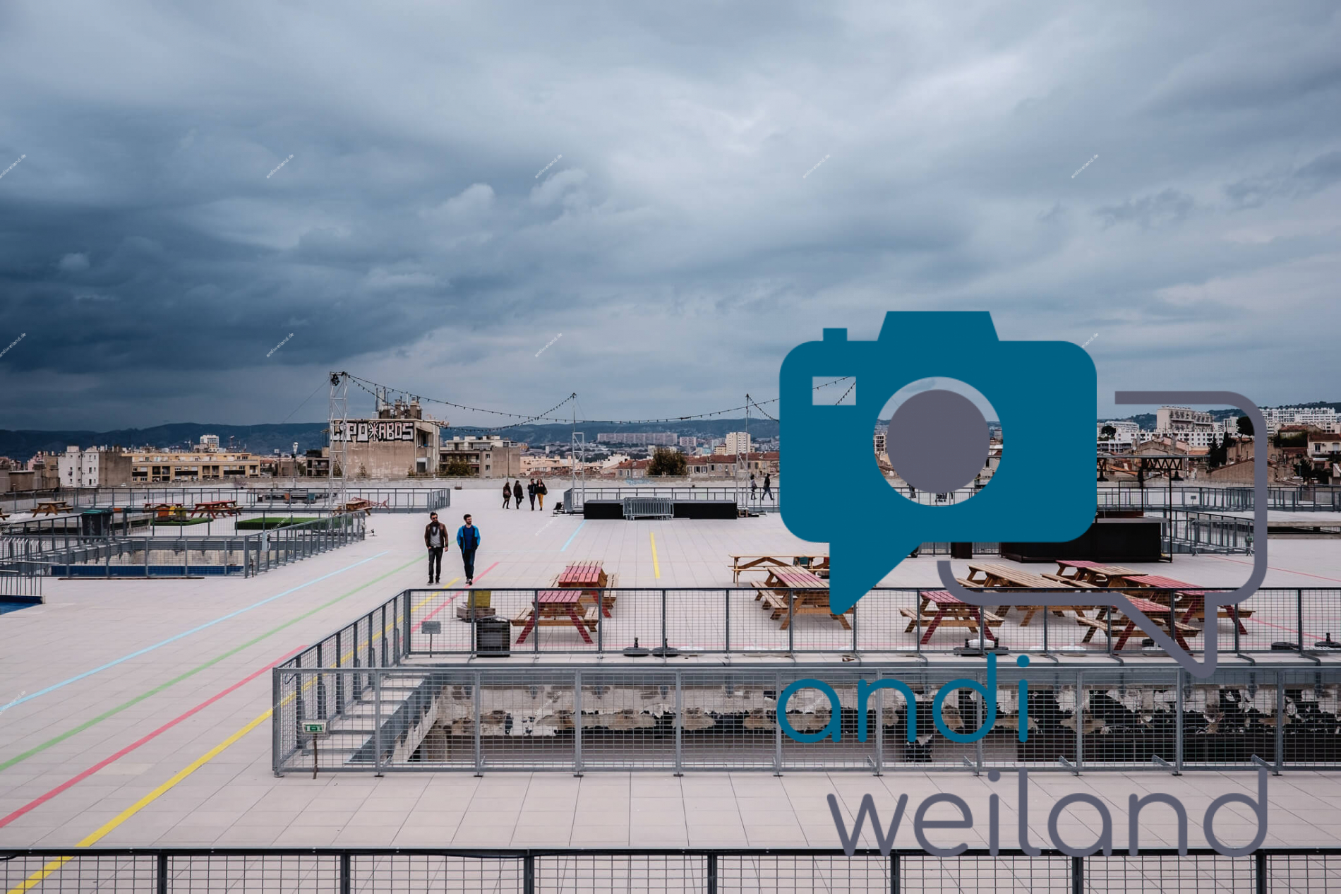 Portrait von einem vollbärtigen Mann mit kurzen Haaren, der in die Kamera lächelt. Er trägt ein Shirt mit einem Fahrrad.