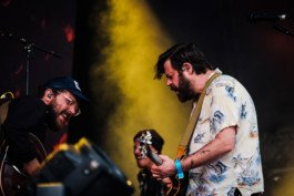 Portrait von einem vollbärtigen Mann mit kurzen Haaren, der in die Kamera lächelt. Er trägt ein Shirt mit einem Fahrrad.