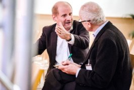 Portrait von einem vollbärtigen Mann mit kurzen Haaren, der in die Kamera lächelt. Er trägt ein Shirt mit einem Fahrrad.