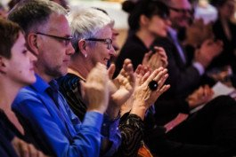 Portrait von einem vollbärtigen Mann mit kurzen Haaren, der in die Kamera lächelt. Er trägt ein Shirt mit einem Fahrrad.