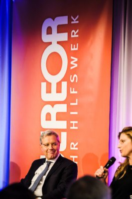 Portrait von einem vollbärtigen Mann mit kurzen Haaren, der in die Kamera lächelt. Er trägt ein Shirt mit einem Fahrrad.