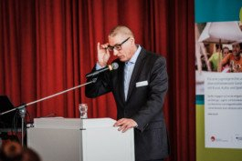  Portrait von einem vollbärtigen Mann mit kurzen Haaren, der in die Kamera lächelt. Er trägt ein Shirt mit einem Fahrrad.