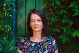 Portrait von einem vollbärtigen Mann mit kurzen Haaren, der in die Kamera lächelt. Er trägt ein Shirt mit einem Fahrrad.