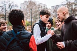 Portrait von einem vollbärtigen Mann mit kurzen Haaren, der in die Kamera lächelt. Er trägt ein Shirt mit einem Fahrrad.