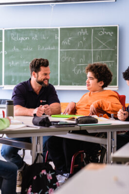 Portrait von einem vollbärtigen Mann mit kurzen Haaren, der in die Kamera lächelt. Er trägt ein Shirt mit einem Fahrrad.