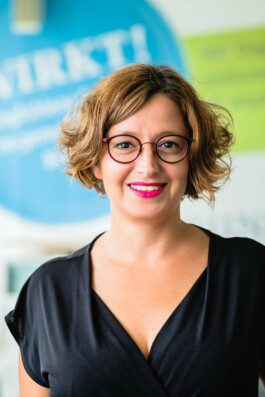 Portrait von einem vollbärtigen Mann mit kurzen Haaren, der in die Kamera lächelt. Er trägt ein Shirt mit einem Fahrrad.