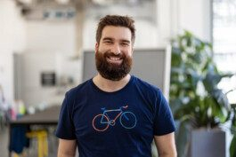 Portrait von einem vollbärtigen Mann mit kurzen Haaren, der in die Kamera lächelt
